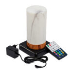 De oplaadbare, waterdichte Tafellamp DORSETTO (cilindervorm, marmer wit grijs houtlook) met afstandsbediening en adapter staat op een zwarte voet, alles weergegeven tegen een witte achtergrond.