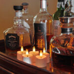 Flessen drank, waaronder Jack Daniel's en LECAT Cognac, staan op een houten dienblad met zes 3D oplaadbare LED-thee/waxinelichtjes (175 uur, timerfunctie, met afstandsbediening) die warm voor hen opgloeien.