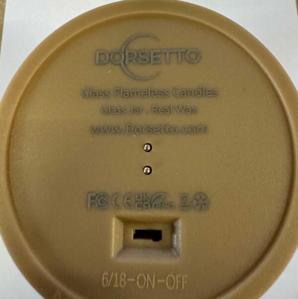 De onderkant van een ronde bruine DORSETTO oplaadbare led kaars uit de 3-delige set (brandtijd 105 uur, met afstandsbediening) toont certificeringssymbolen, website, 6/18-ON-OFF schakelaar, en een poort voor magnetisch opladen-ideaal voor restaurants.