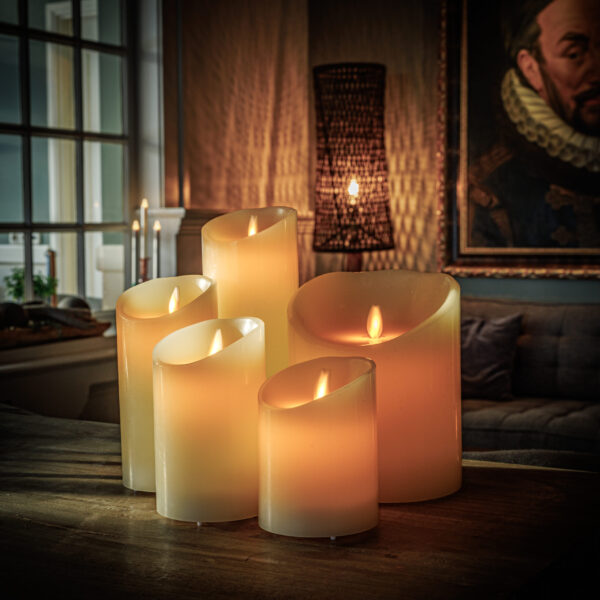 Een gezellige woonkamer gloeit warm als vijf vlamloze kaarsen en een Oplaadbare LED dinerkaars 270mm (set van 12, warm wit, batterij van 130 uur, afstandsbediening) een houten tafel bij een bank en een groot portret verlichten.