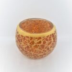 De Waxinelichthouder 8,5 CM Dorsetto mozaïek oranje heeft een levendig oranje mozaïekglasontwerp met een metallic gouden rand, tegen een effen witte achtergrond.