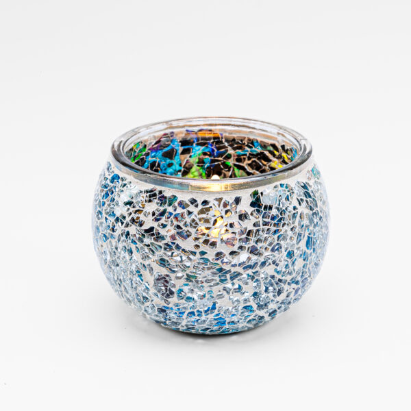 De Waxinelichthouder 9 CM Dorsetto mozaïek multicolor heeft een rond glazen ontwerp met blauwe en zilveren reflecterende tegels, die een brandende kaars vasthouden tegen een effen witte achtergrond.