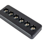 De Oplaadstation zwart magnetisch DORSETTO voor 6 dinerkaarsen is een slank zwart oplaaddock met zes ronde sleuven, ideaal voor het opladen van maximaal zes dinerkaarsen of andere kleine apparaten, afgebeeld op een witte achtergrond.