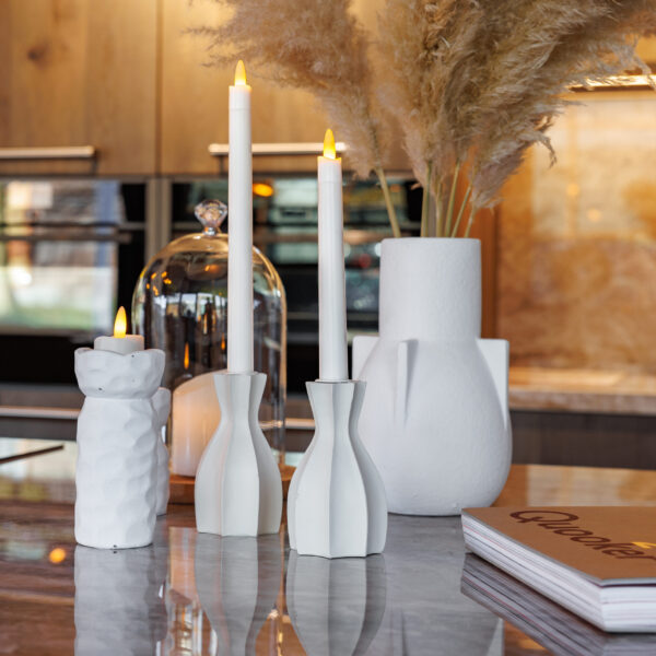 Een close-up van een modern aanrecht met witte keramische vazen, 3D oplaadbare LED-thee/waxinelichtjes 175 uur (6 stuks, timerfunctie, afstandsbediening), pampagras en een gesloten kookboek op een marmeren oppervlak.