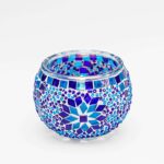 Theelichthouder 9 CM Dorsetto blauw: een ronde glazen kandelaar, versierd met blauwe, paarse en witte geometrische mozaïektegeltjes en een stervormig ontwerp. Gefotografeerd tegen een effen witte achtergrond.