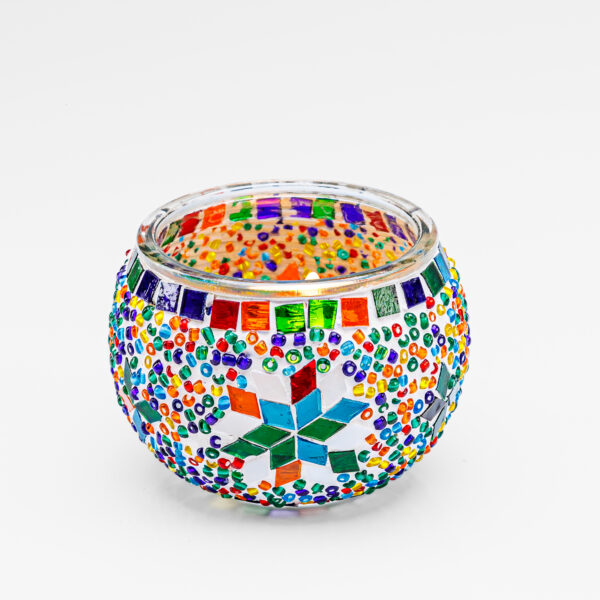Waxinelichthouder 9 CM Dorsetto regenboog: Een kandelaar van helder glas versierd met kleurrijke mozaïekkralen en een centrale ster, met levendige rode, blauwe, groene, oranje en gele geometrische patronen.