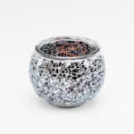 Theelichthouder zwart 9 CM DORSETTO: Een ronde glazen kandelaar met een mozaïek van kleine, onregelmatige spiegeltjes die het licht weerkaatsen; de gladde, donkere binnenkant contrasteert met de sprankelende buitenkant op een witte achtergrond.