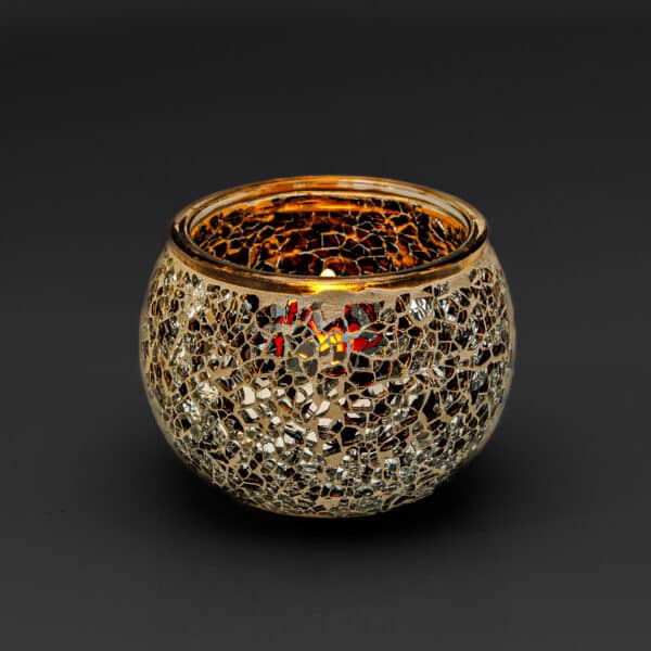 De Theelichthouder zwart 9 CM DORSETTO, een ronde glazen houder met een mozaïek van goud en zilver, straalt een warme gloed uit van de brandende kaars, die prachtig afsteekt tegen een donkere achtergrond.