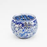 Theelichthouder 9 cm DORSETTO donker blauw: Een ronde, heldere glazen kandelaar met een blauw en zilver mozaïekpatroon, afgebeeld tegen een effen witte achtergrond.