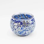 De Theelichthouder 9 cm DORSETTO donker blauw is een ronde glazen kandelaar versierd met een mozaïekpatroon van donkerblauwe, zilveren en heldere stukjes tegen een witte achtergrond.