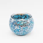 Theelichthouder 9 CM Dorsetto lichtblauw: een ronde glazen kandelaar met een lichtblauw en zilverkleurig mozaïekontwerp en spiegelende accenten, weergegeven op een effen witte achtergrond.