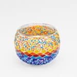 Theelichthouder 3 colormix 9 CM Dorsetto: een ronde glazen kandelaar met kleurrijke mozaïeksteentjes en kralen in levendige rode, gele, oranje, blauwe en paarse patronen op een witte achtergrond.