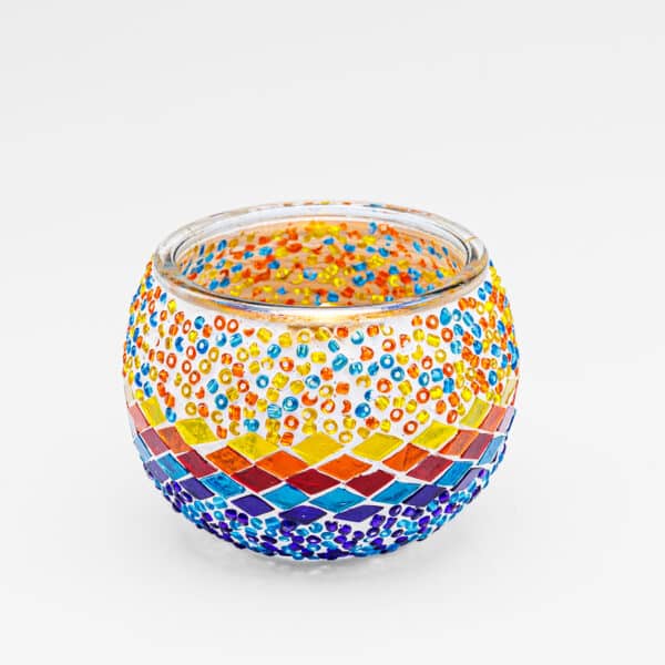 Theelichthouder 3 colormix 9 CM Dorsetto: een ronde glazen kandelaar met kleurrijke mozaïeksteentjes en kralen in levendige rode, gele, oranje, blauwe en paarse patronen op een witte achtergrond.