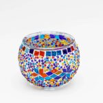 Theelichthouder gekleurde spikkels 9 CM DORSETTO: een ronde glazen kandelaar versierd met kleurrijke mozaïeksteentjes en kralen in blauw, rood, geel, oranje en paars, afgebeeld op een effen witte achtergrond.