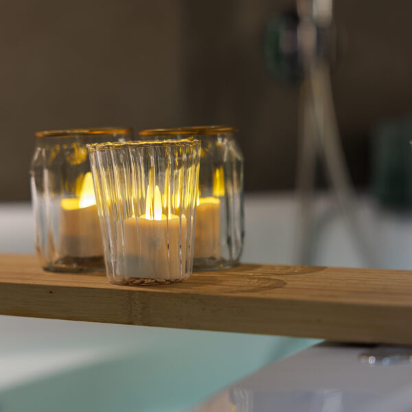 3 waxinelichtjes in glazen potjes op plank